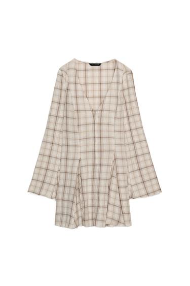 Front view of a short ecru dress with a check pattern, a V-neck, long flared sleeves, and a front fastening with metal hooks.