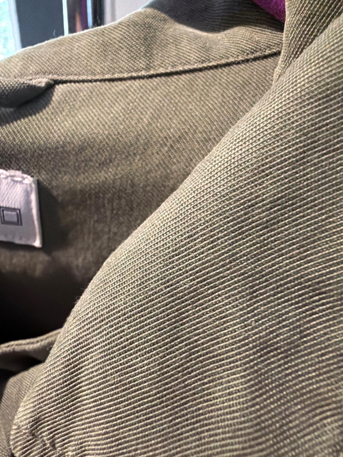 Close-up of thick ribbed fabric in olive green, highlighting the texture of its diagonal lines and a white label.