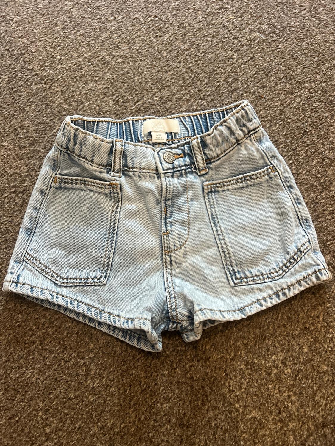 Light blue denim shorts with an elasticated waist and front pockets, on a brown rug.