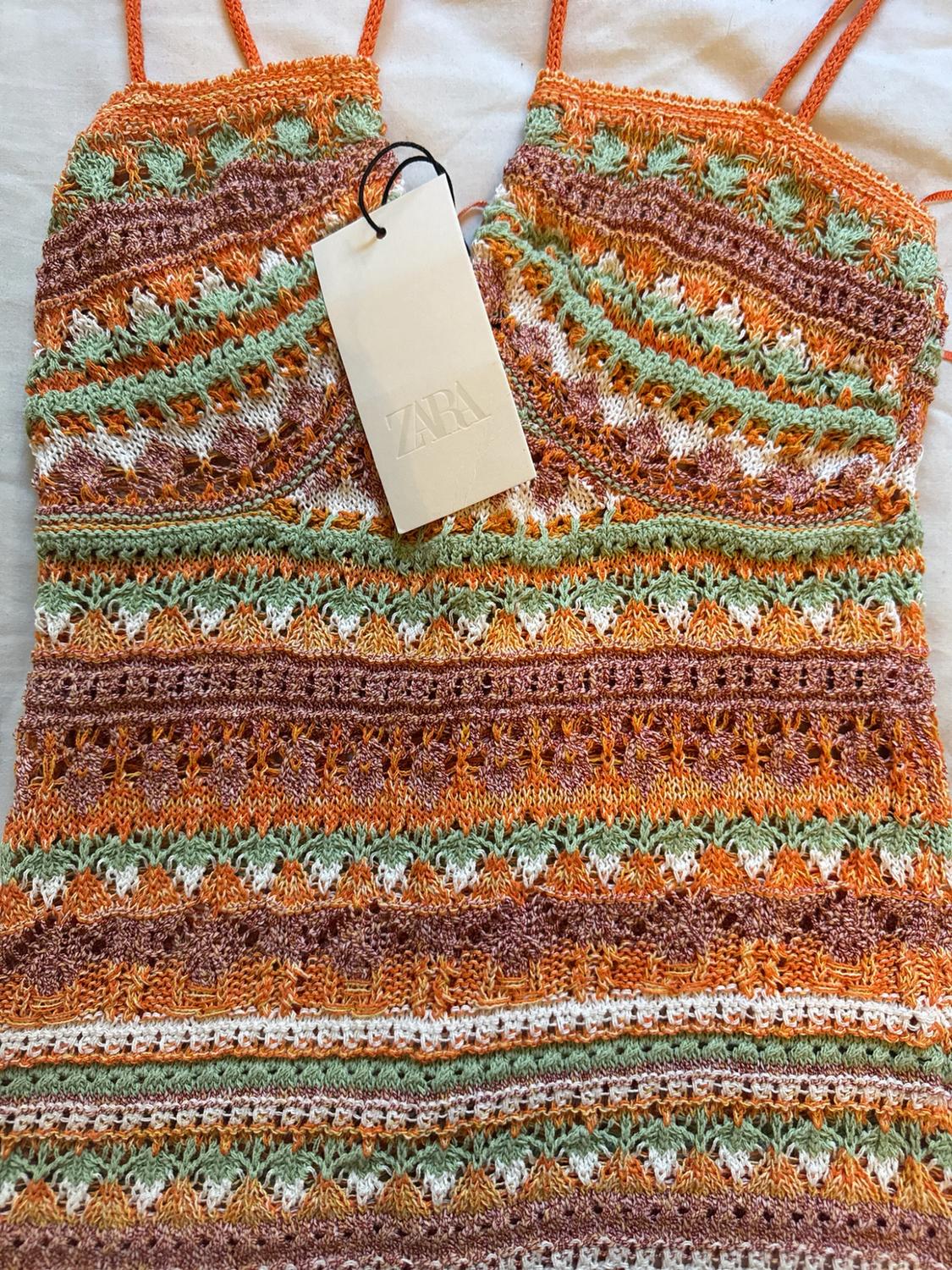 Knitted open-work top with zigzag stripes in shades of orange, green, white and brown. It features delicate straps and a label with the text Zara.