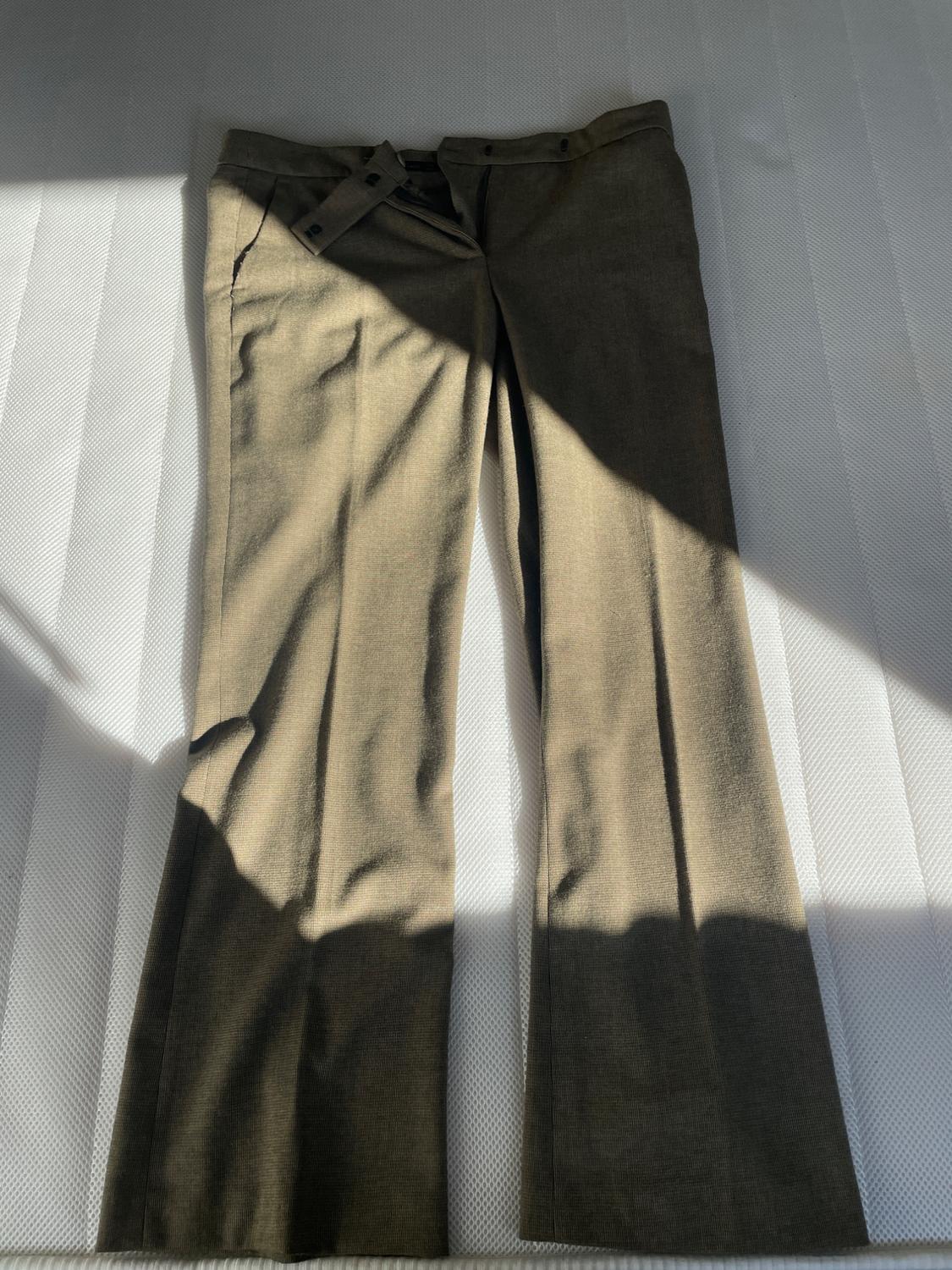 Front view of brown trousers with side pockets and button fastening.