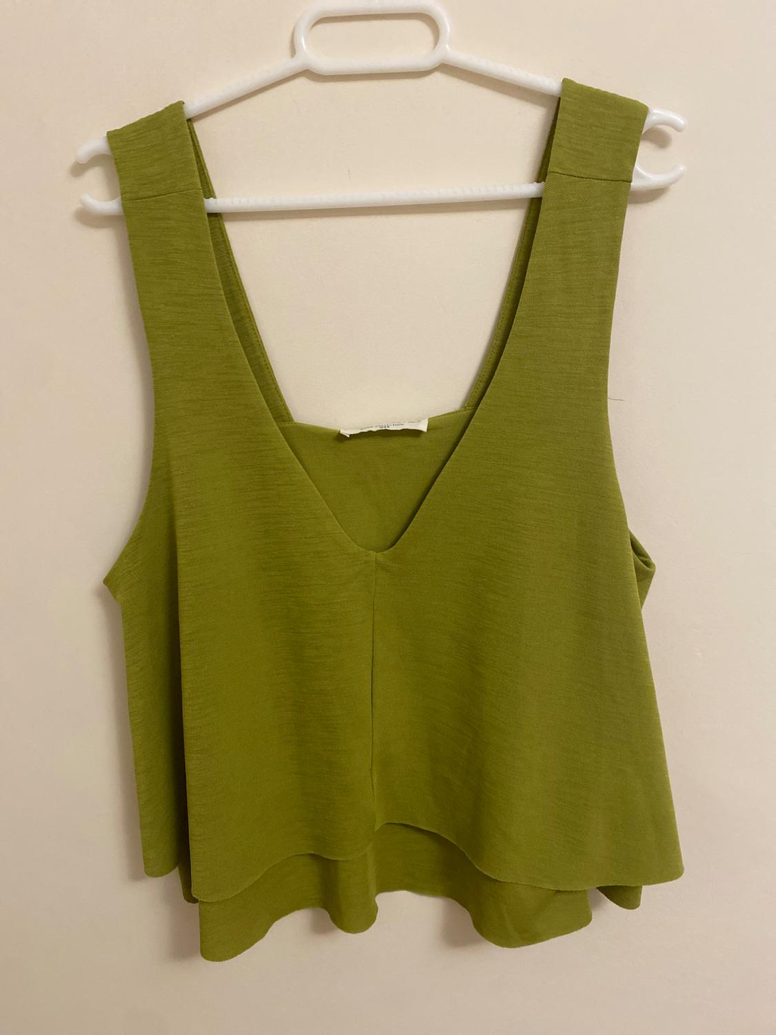 Front view of a sleeveless green V-neck blouse.