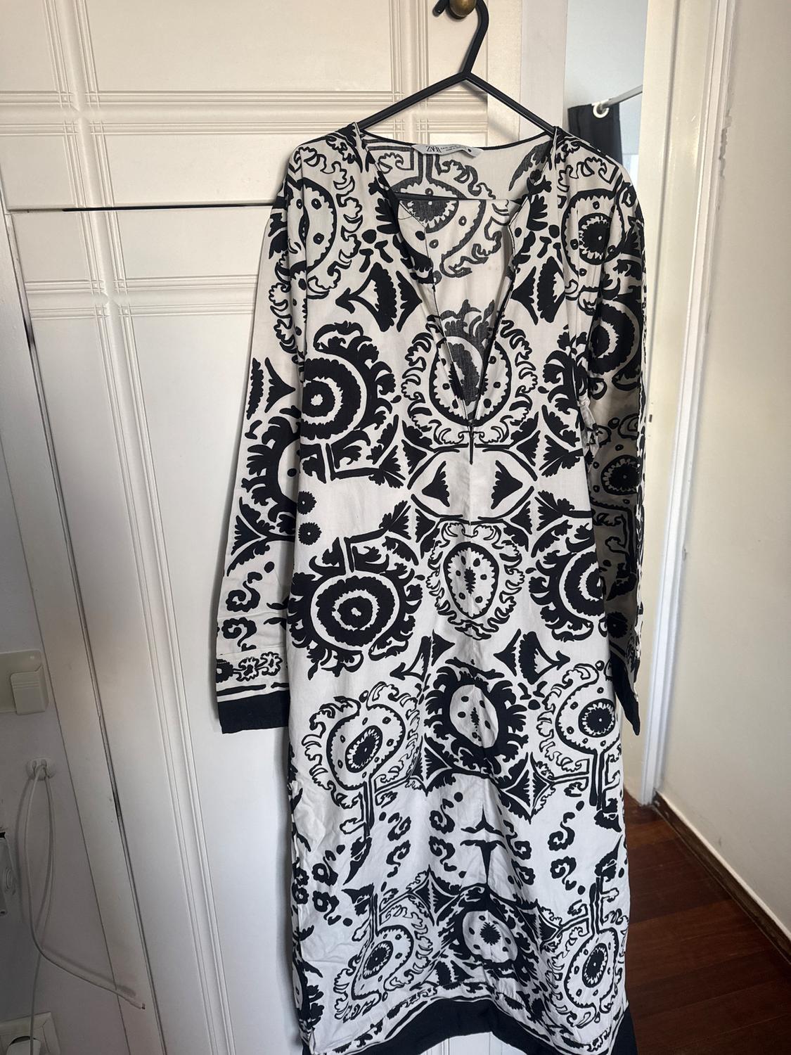 Dress hanging on a hanger, with a black and white geometric and floral pattern, in a well-lit room.