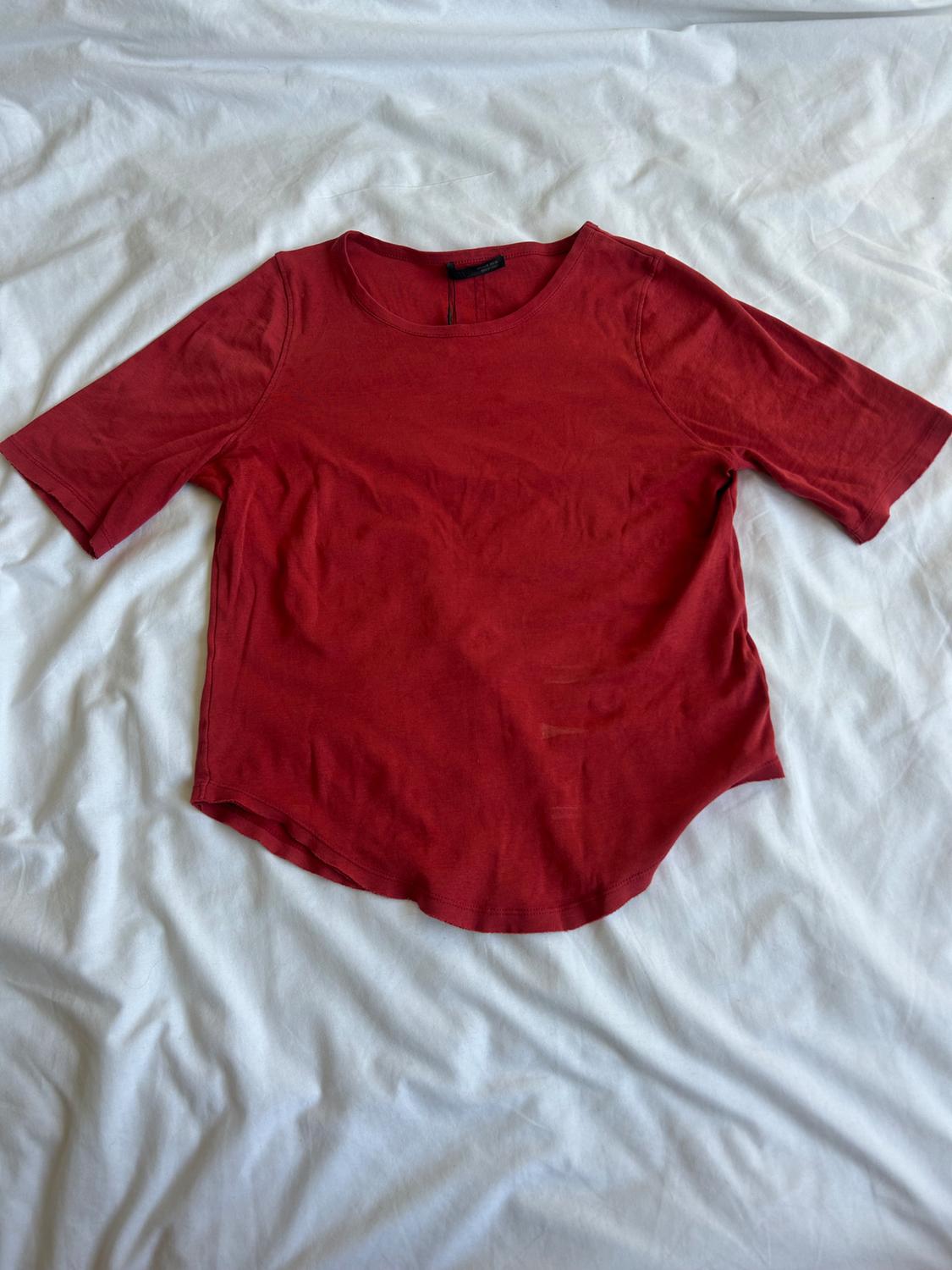 Red short-sleeved, crew-neck T-shirt on a wrinkled white surface.