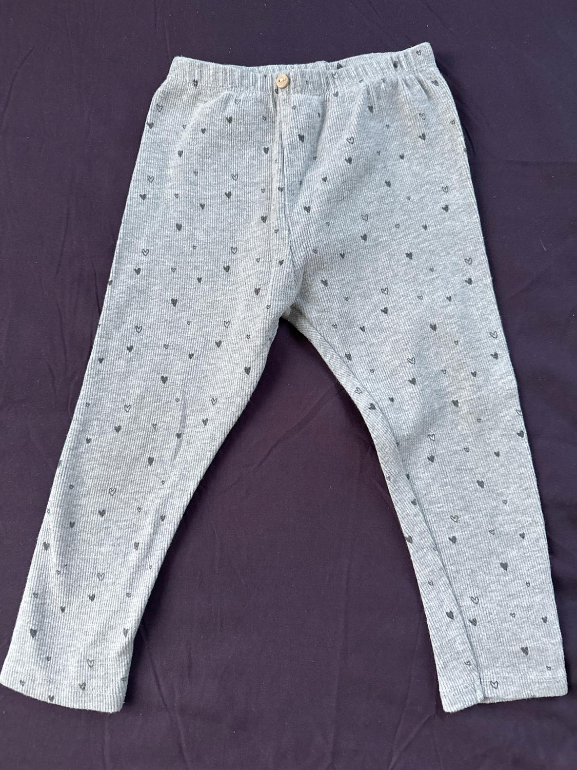 Front view of gray pants with a small heart print and a button at the waist