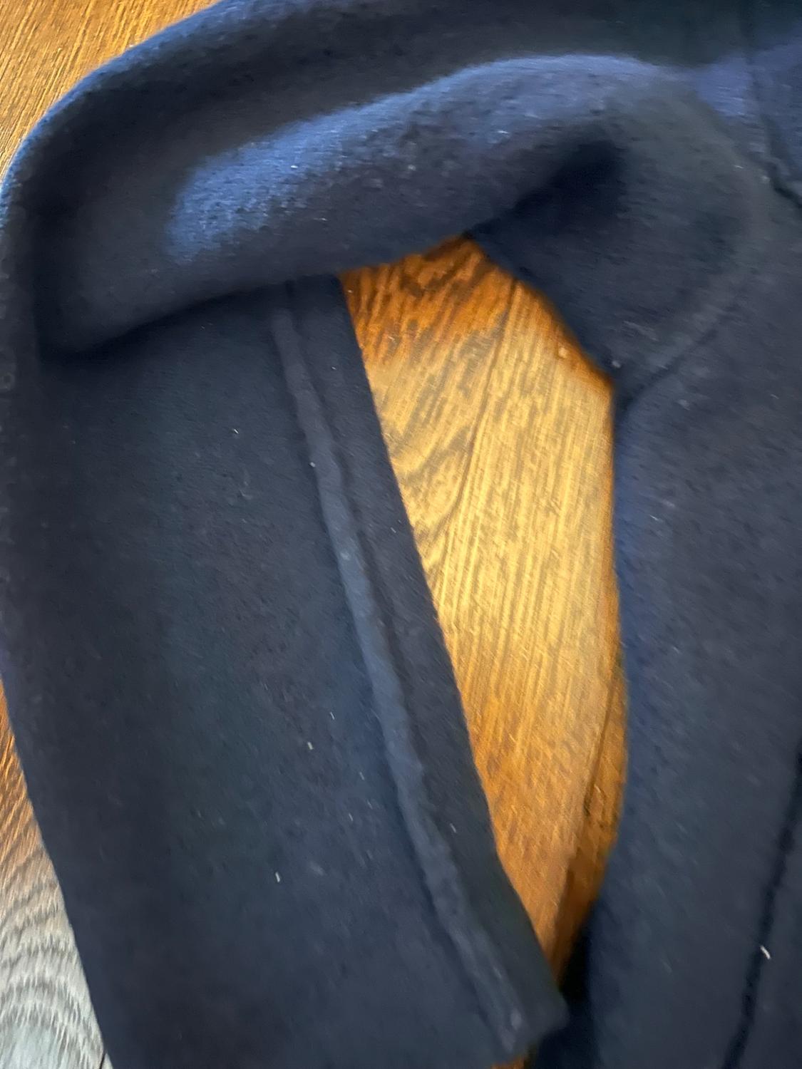 Black wool fabric on a wooden surface. The texture of the fabric is visible, showing a smooth and warm finish.