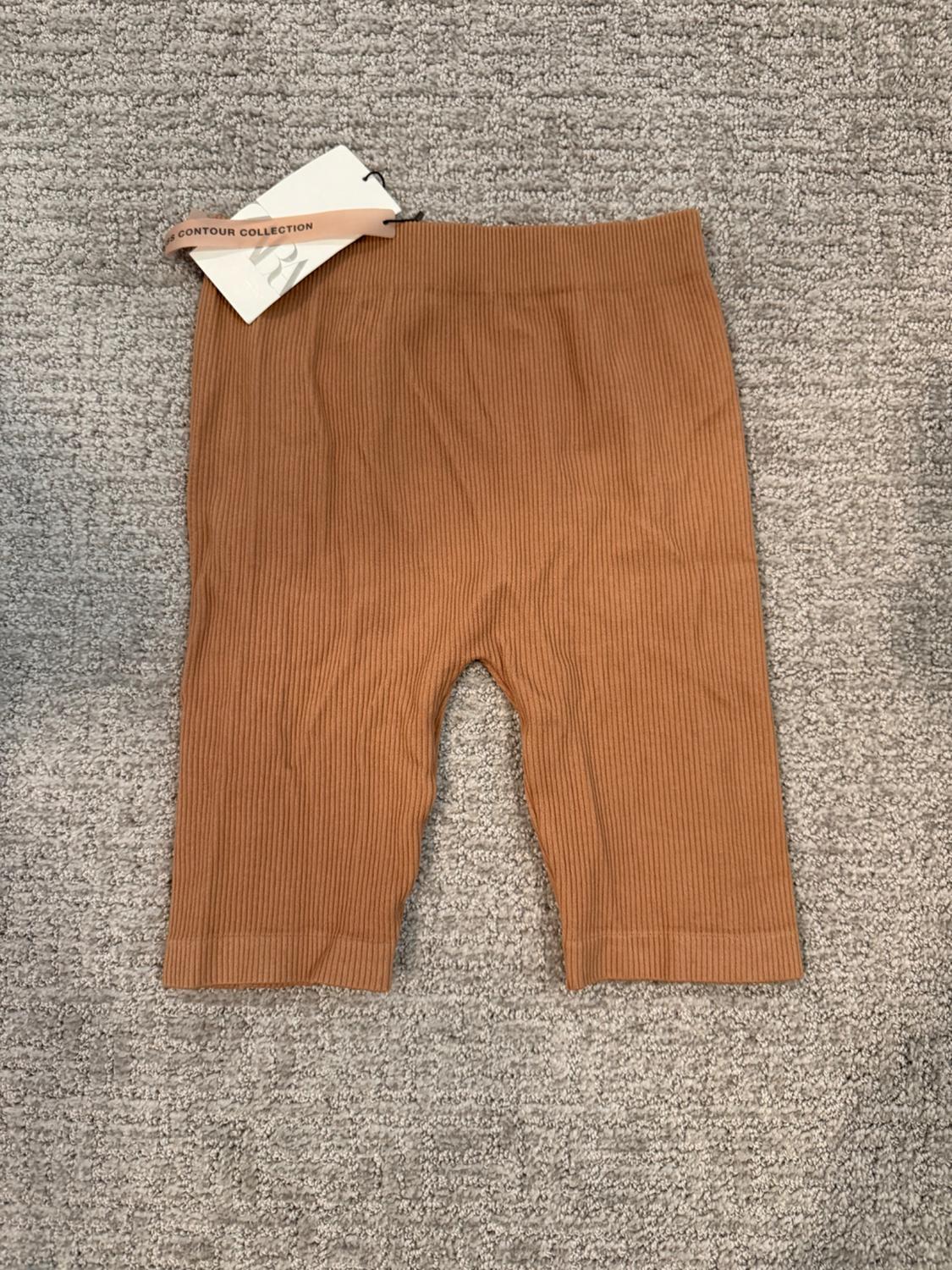 Light brown ribbed shorts on a gray rug. Label with the text CONTOUR COLLECTION.