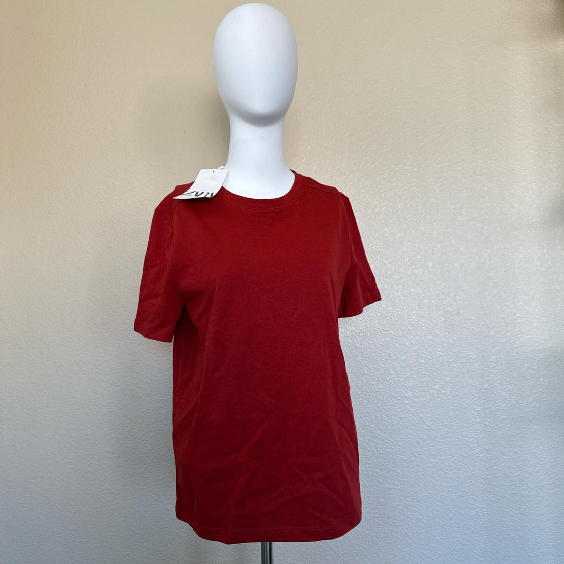 Mannequin with a red short-sleeve t-shirt on a neutral background. White label visible on the collar.