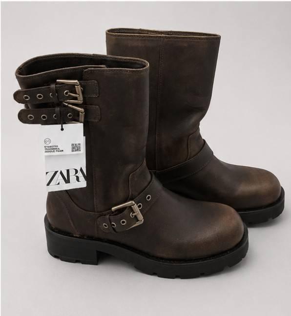 Brown boots with buckles and thick black soles on a light background. They have a white label with the text ZARA.