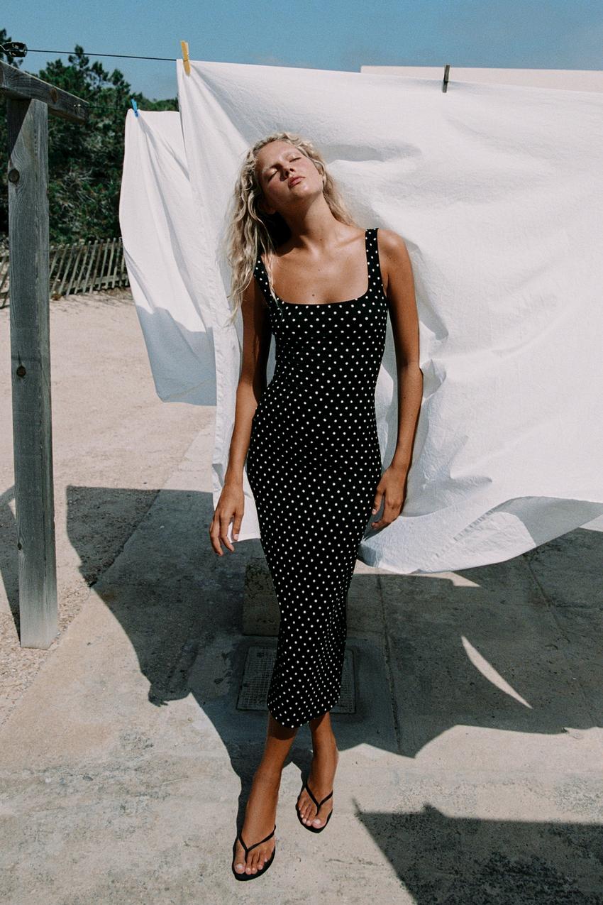 Black bodycon midi dress outfit with white polka dot print, square neckline, and straps, paired with black sandals.