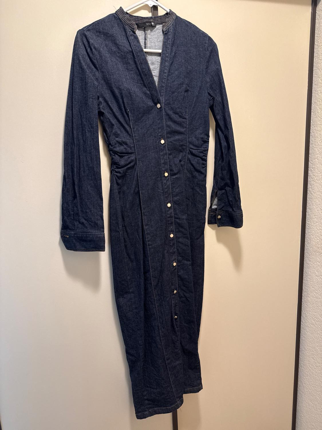Dark blue long-sleeved denim dress, V-neck, front buttons and gathered waist,
hanging on a hanger.