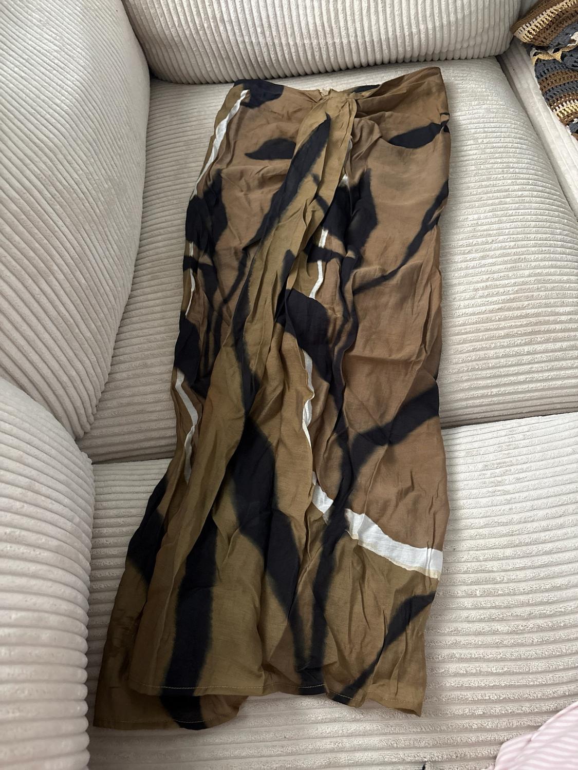 Long brown skirt with an abstract black and white pattern, spread out on a beige corduroy sofa.