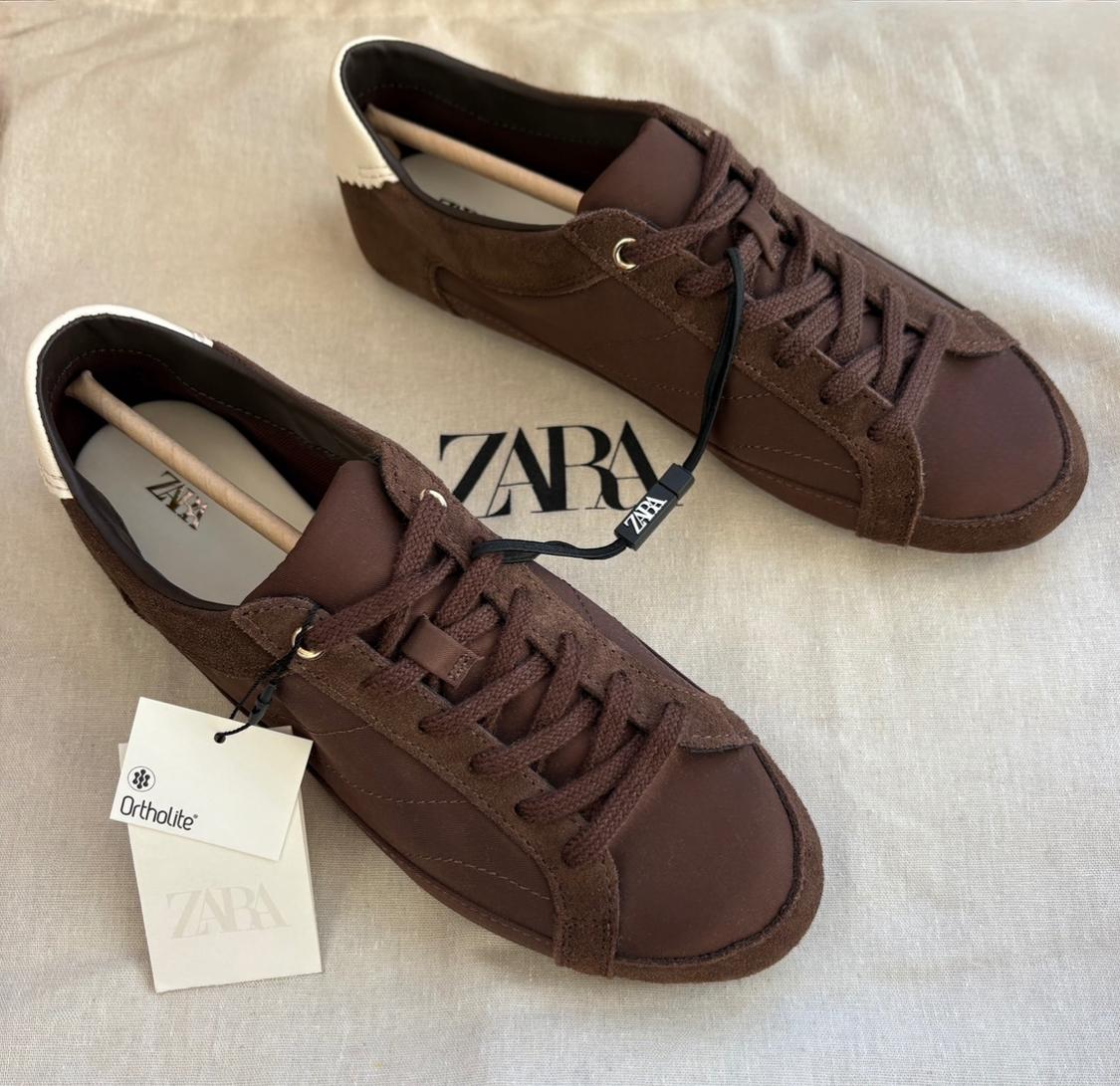 Brown lace-up trainers with a white heel on fabric. Visible text: ZARA and Ortholite on the background and labels.
