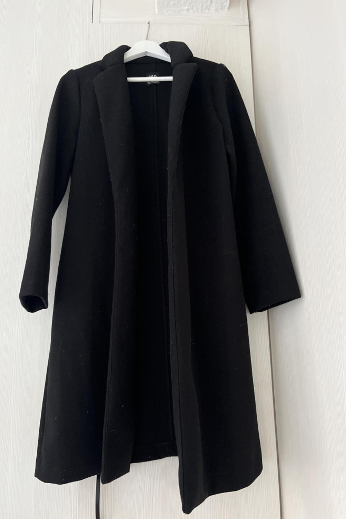 Front view of a long black coat with lapels and long sleeves.