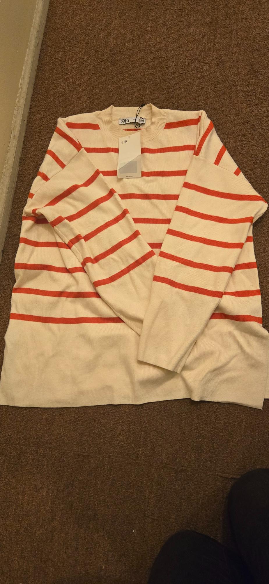 Front view of a red and white striped jumper with a crew neck and long sleeves.