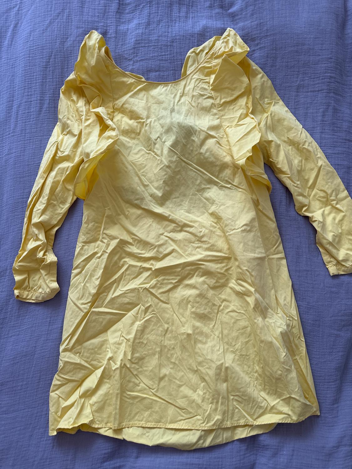 Creased yellow dress with ruffled shoulders, on a blue fabric.