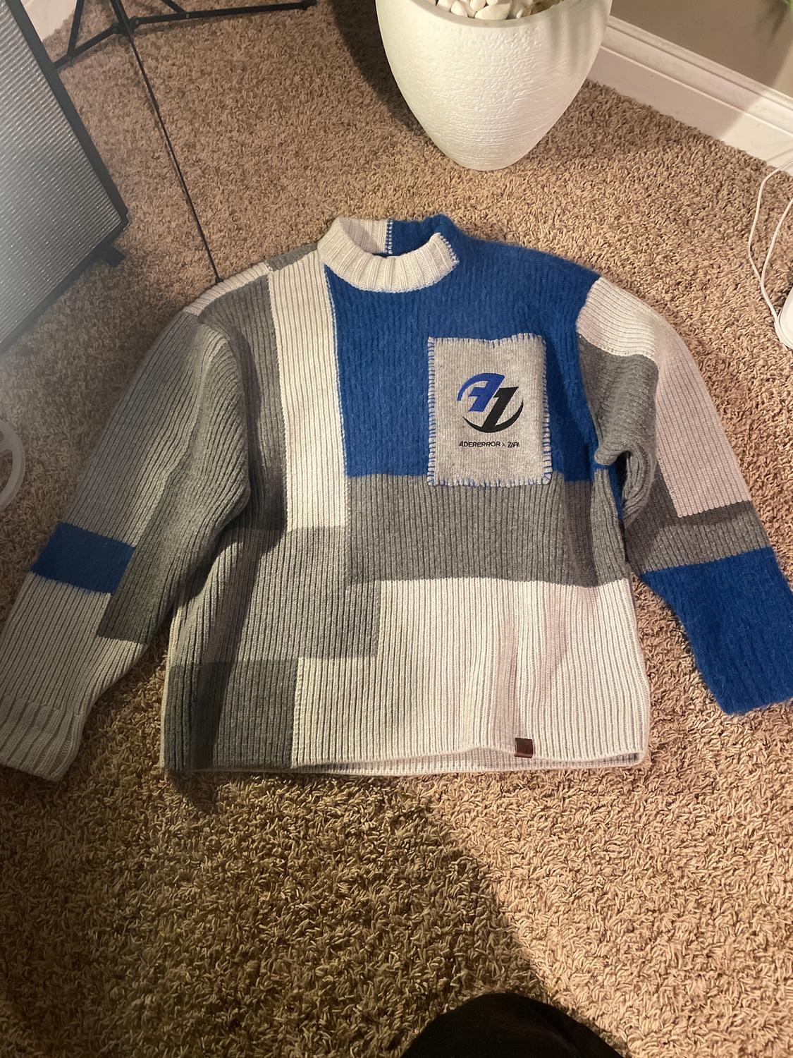Knitted jumper in blue, grey, and white tones with a geometric design. Chest pocket with "Adererror 2/2R" logo.