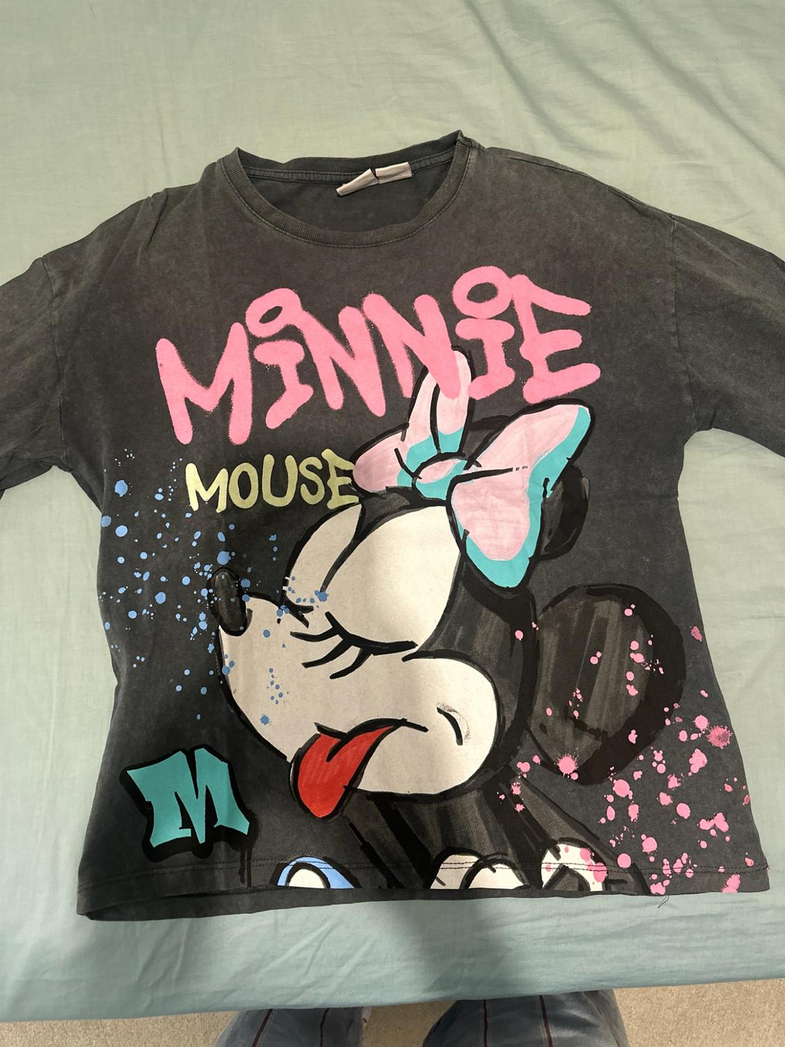 Dark grey t-shirt on a light background with a graphic of Minnie Mouse winking and splatters. Text: MINNIE, MOUSE, M.