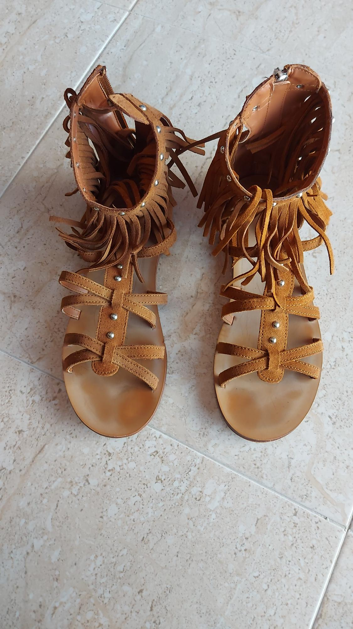 Top view of brown sandals with fringe and studs.