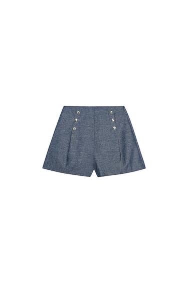 Front view of blue shorts with silver buttons and decorative pleats at the front.