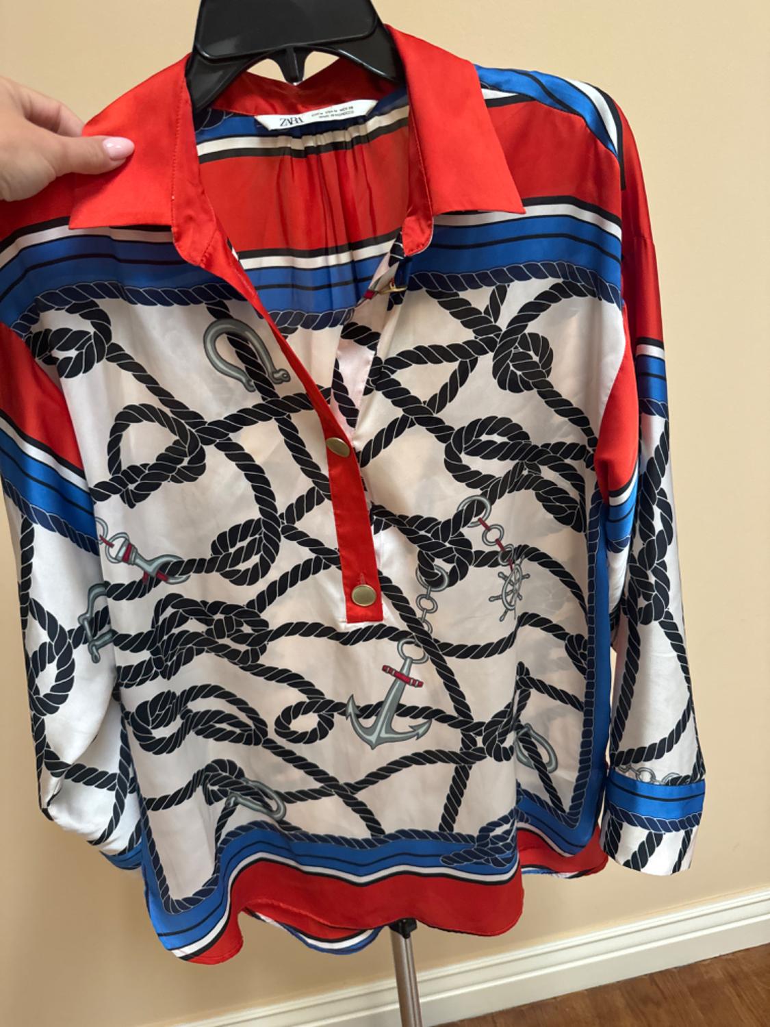 Front view of a blouse with a nautical rope and anchor print in red, blue, and white with a red collar.