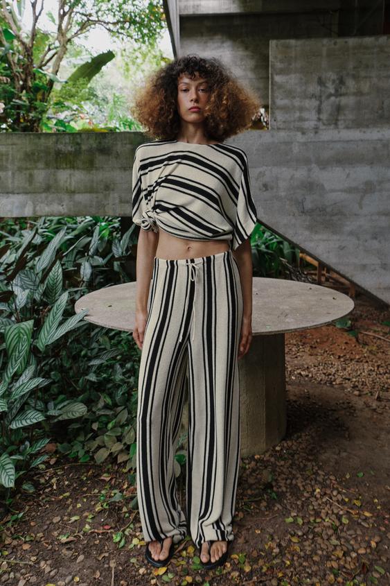 Souprava topu a kalhot s černobílými pruhy, top s bočním uzlem a kalhoty s širokými nohavicemi.