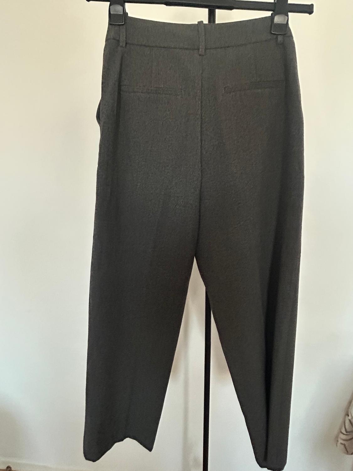 Grey trousers hanging on a black hanger against a white background. The fabric appears to have a soft texture.