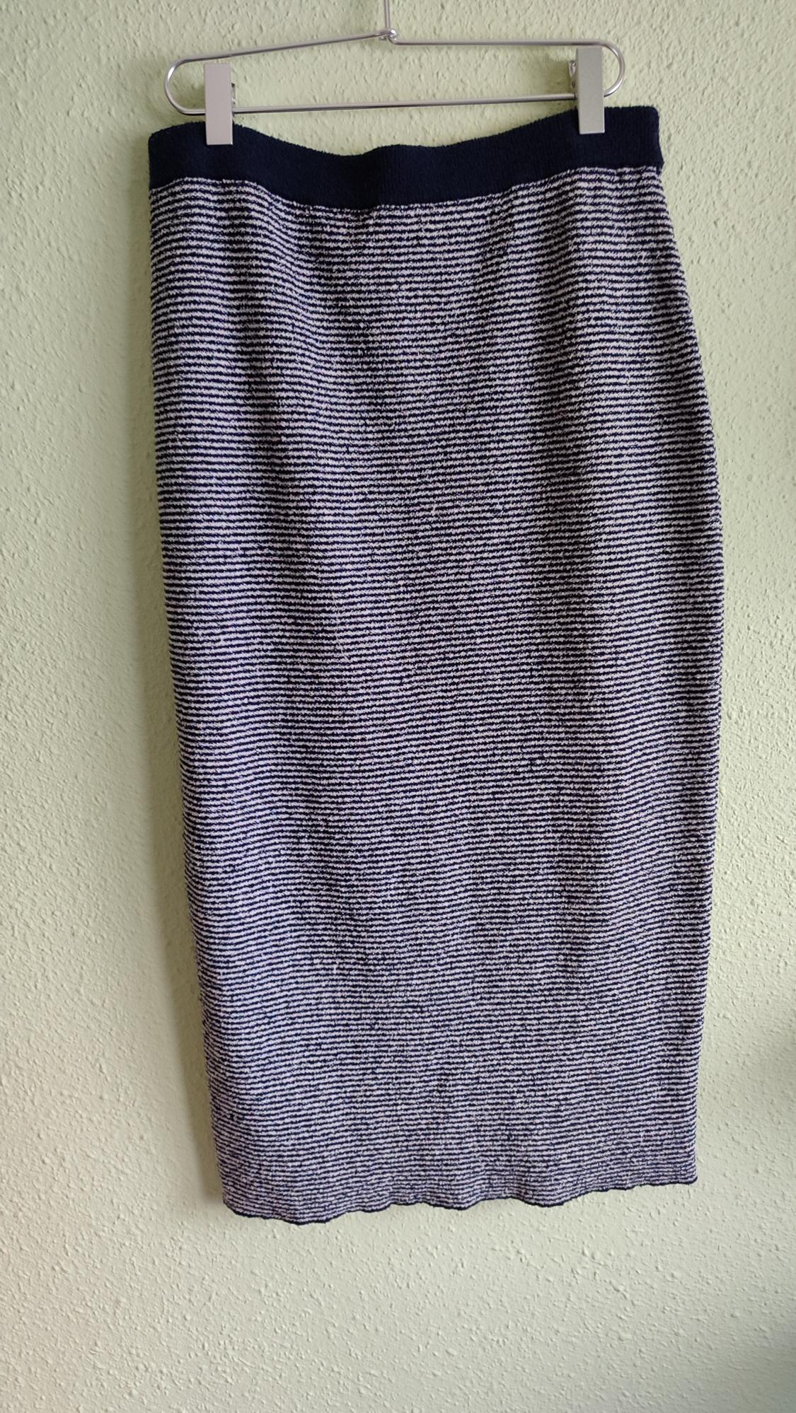 Blue and white horizontal striped midi skirt with a dark waistband, hanging on a hanger against a light green wall.