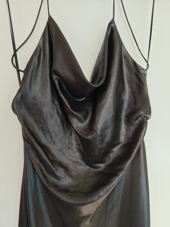 Shiny black dress with spaghetti straps and draped neckline, hanging on a white background.