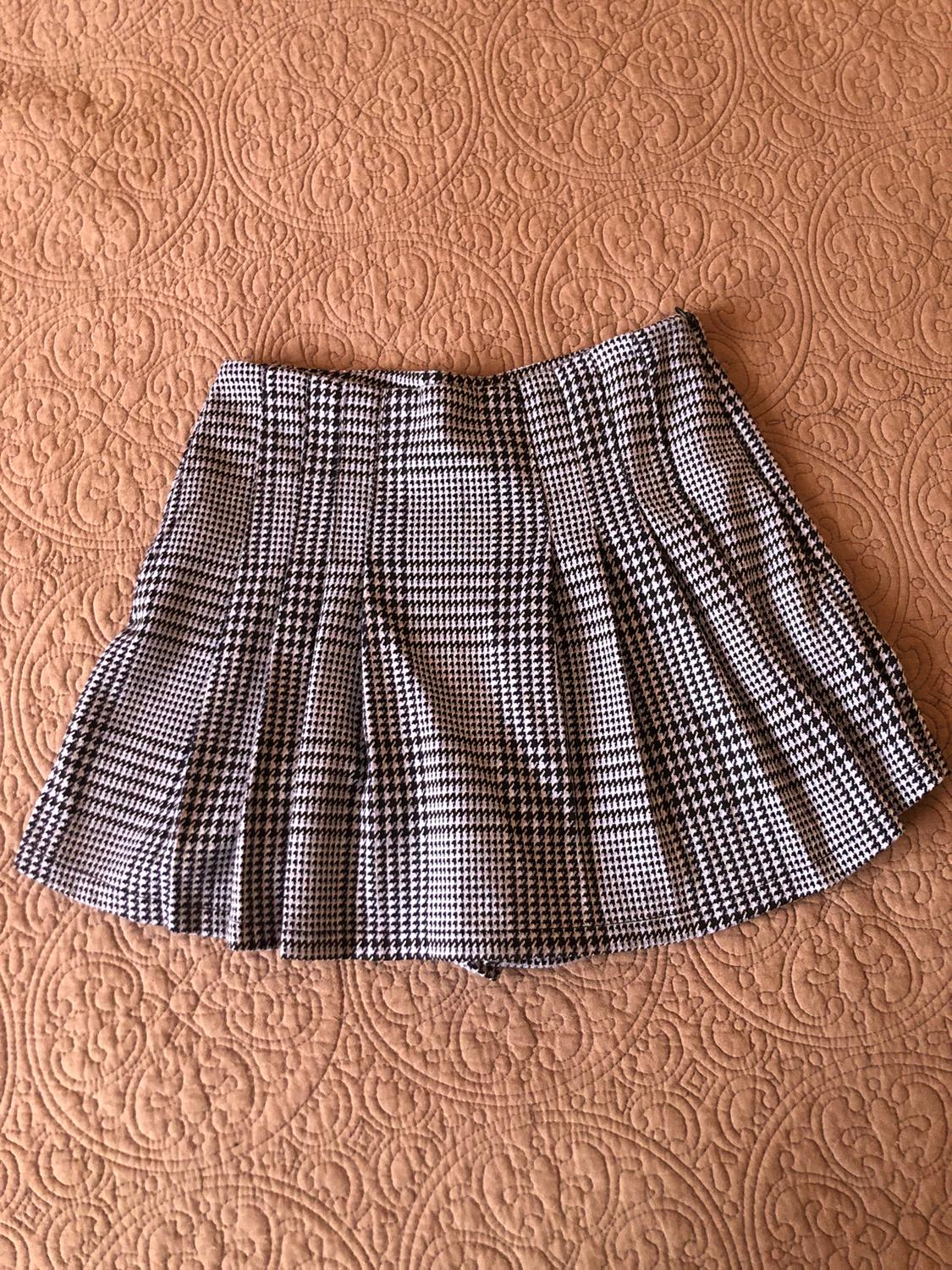 Black and white checked mini skirt on a beige bedspread with a circular pattern design.