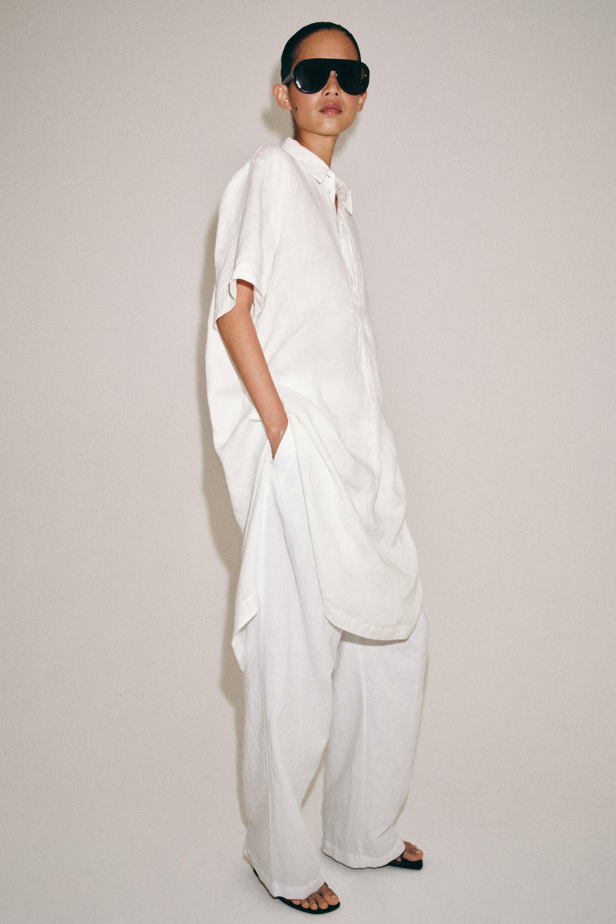 Set consisting of a white, short-sleeved long shirt with a collar, side slits, and pockets, and white wide-leg pants.