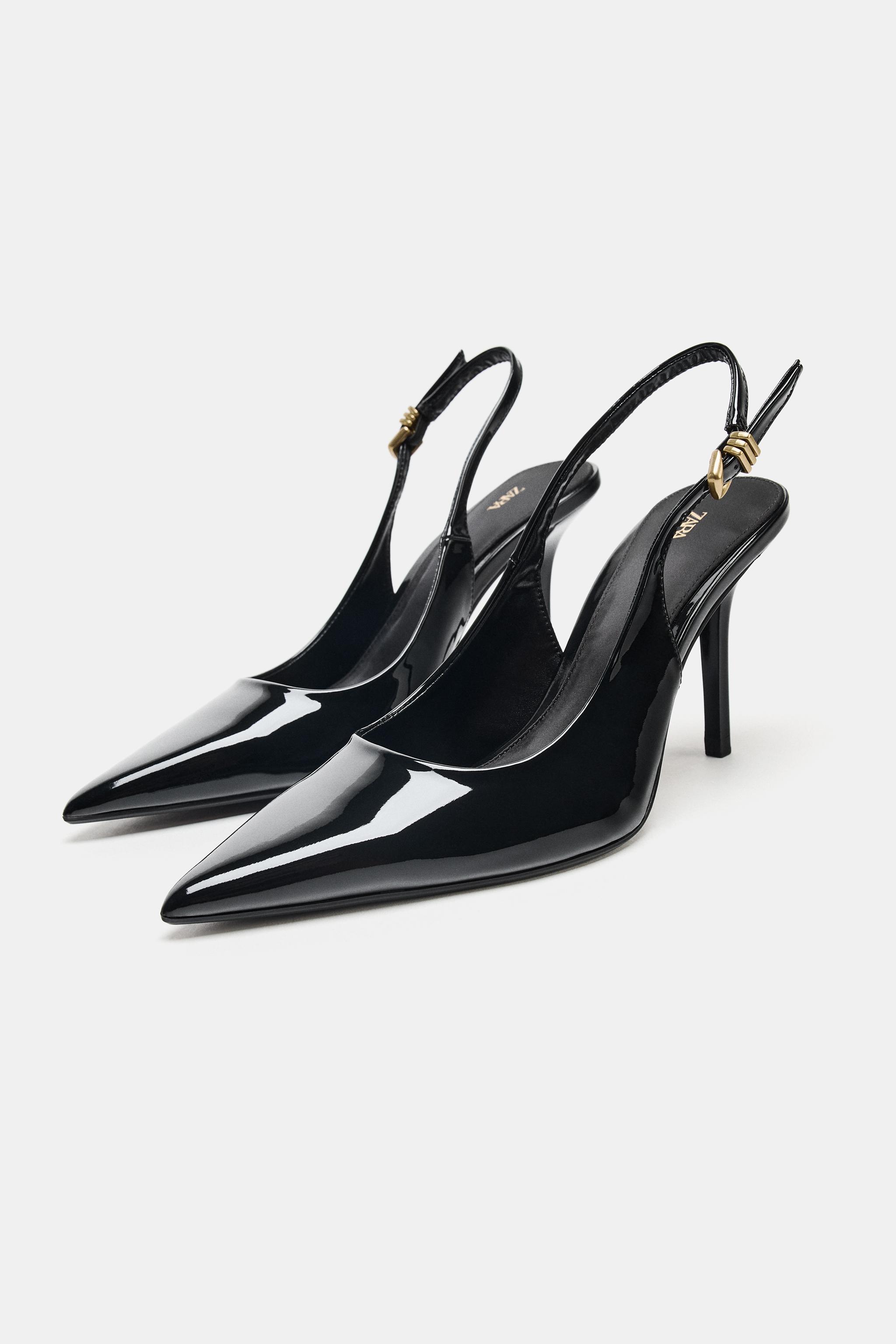 Black high heels with a pointed toe and adjustable heel strap, featuring a gold buckle detail.