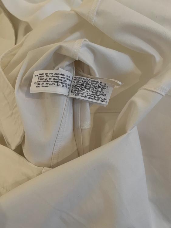 White fabric composition label, showing 97% cotton and 3% elastane, with care instructions in various languages.