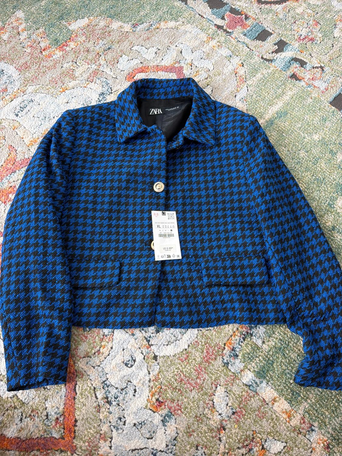 Blue-and-black houndstooth jacket with gold buttons on a patterned carpet. Text: ZARA, XL, US$89.