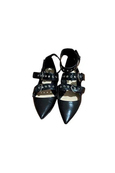 Black pointed-toe shoes with multiple straps, buckles, and silver metallic details on a white background.