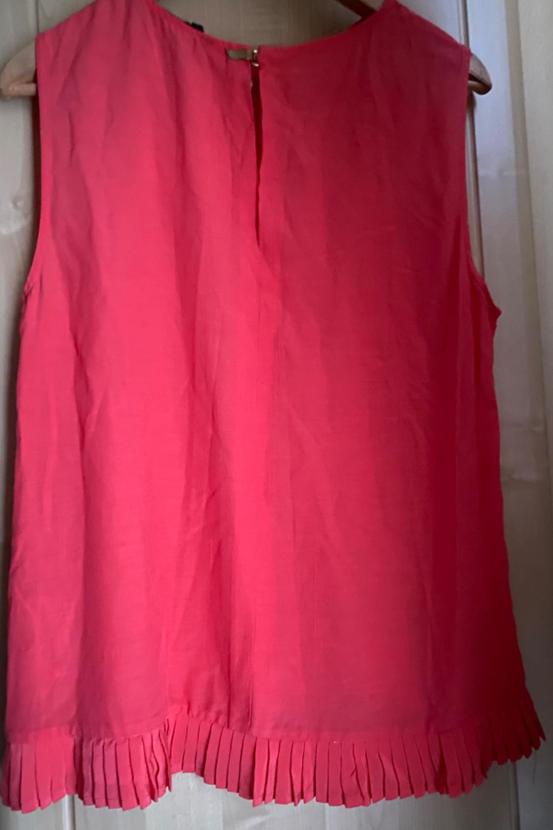 Front view of a pink sleeveless blouse with pleats on the bottom hem.