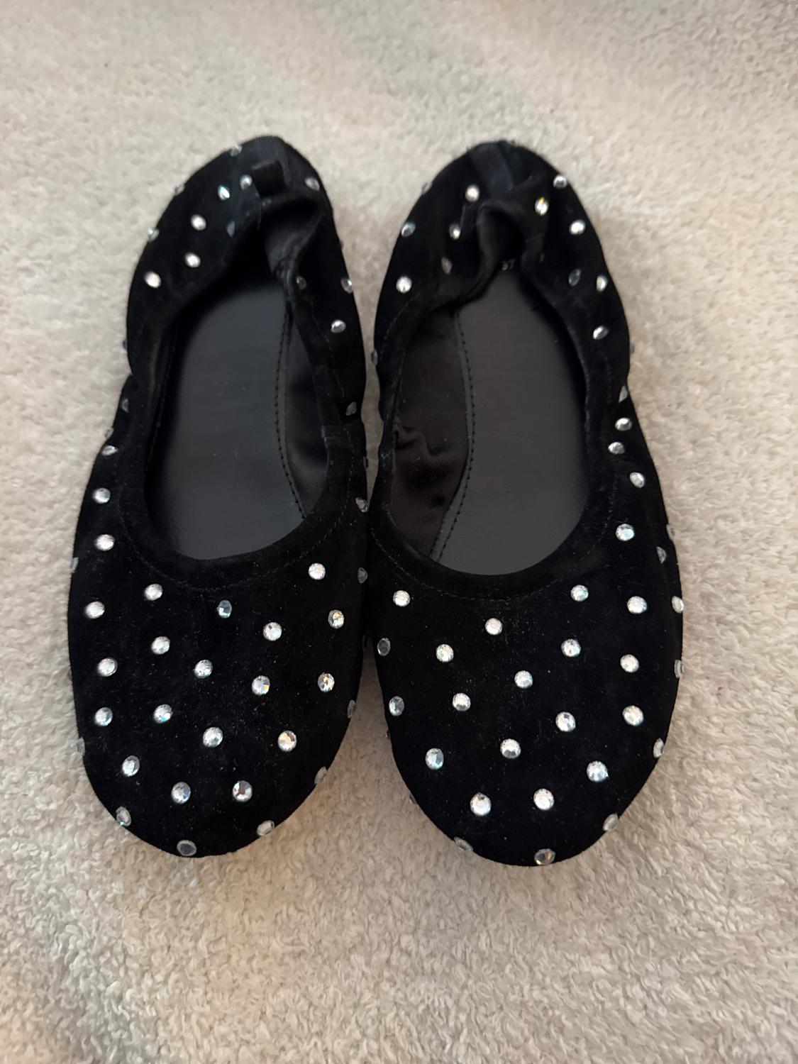 Front view of black sneakers with shiny studs.