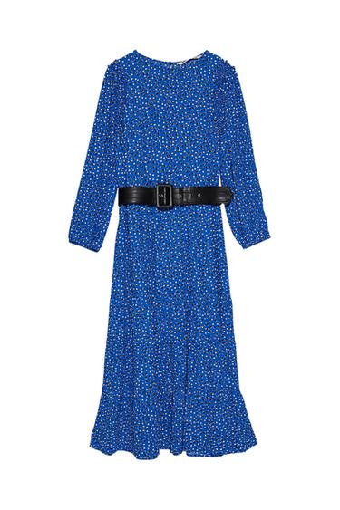 Blue dress with a white polka dot print and a wide black belt. Long sleeves and a flowing cut.