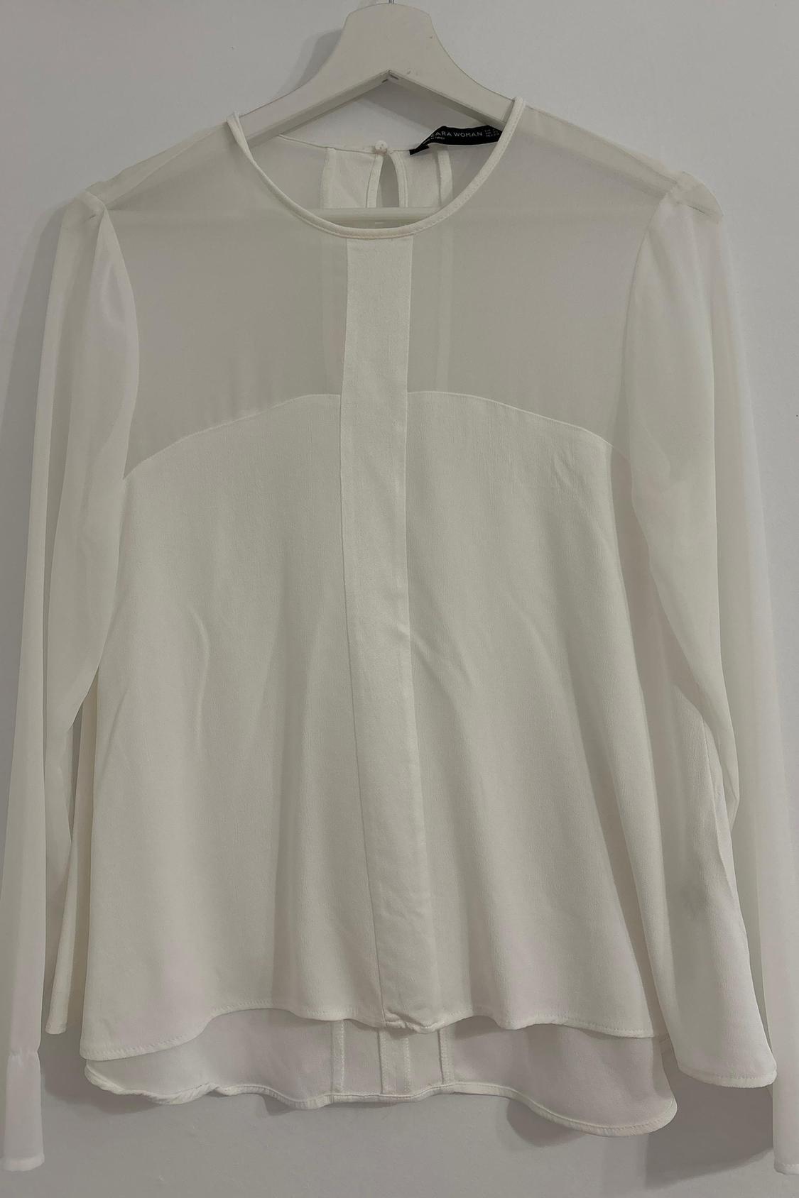 Front view of a white blouse with sheer shoulders and back fastening.