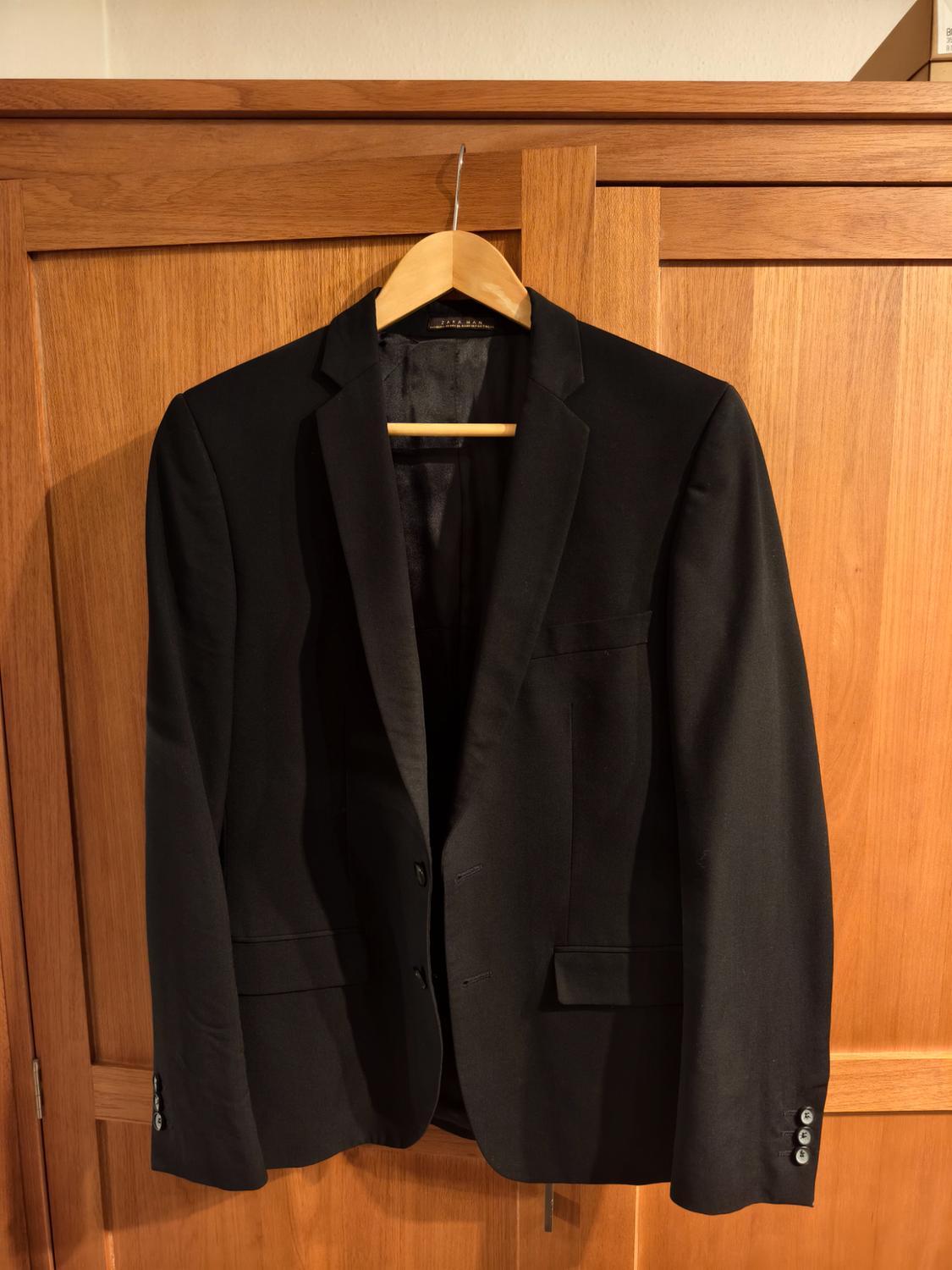 Front view of a black jacket with lapels and front pockets.