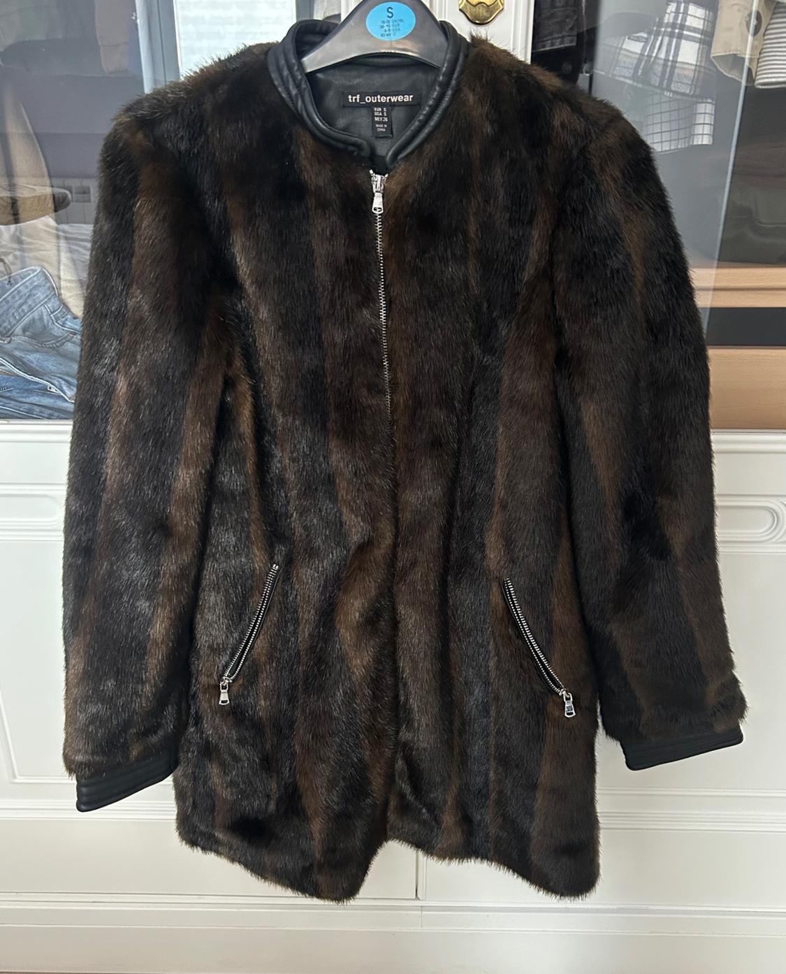 Dark brown faux fur coat with zip and pockets, hanging on a black hanger with "trf_outerwear" tag.
