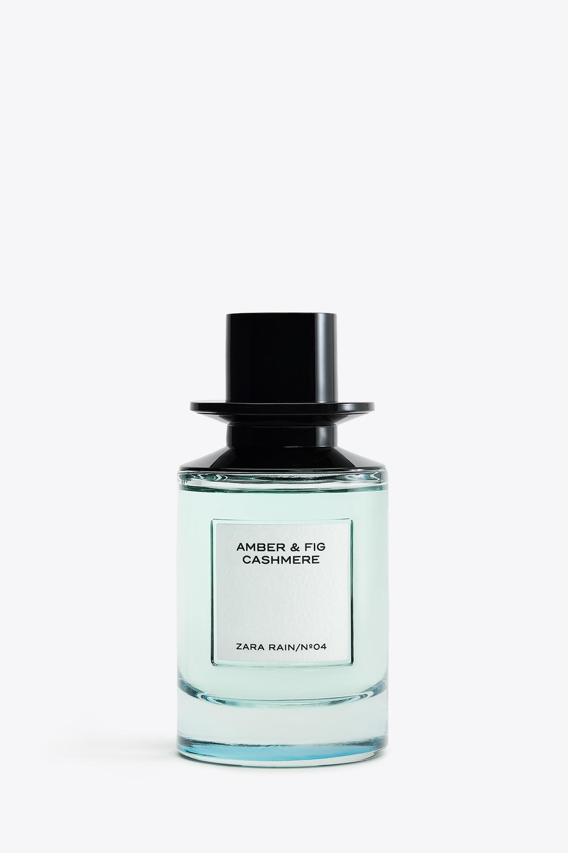 Steklenička parfuma z besedilom "AMBER & FIG CASHMERE" in "ZARA RAIN/Nº04" na beli etiketi, črn pokrovček.
