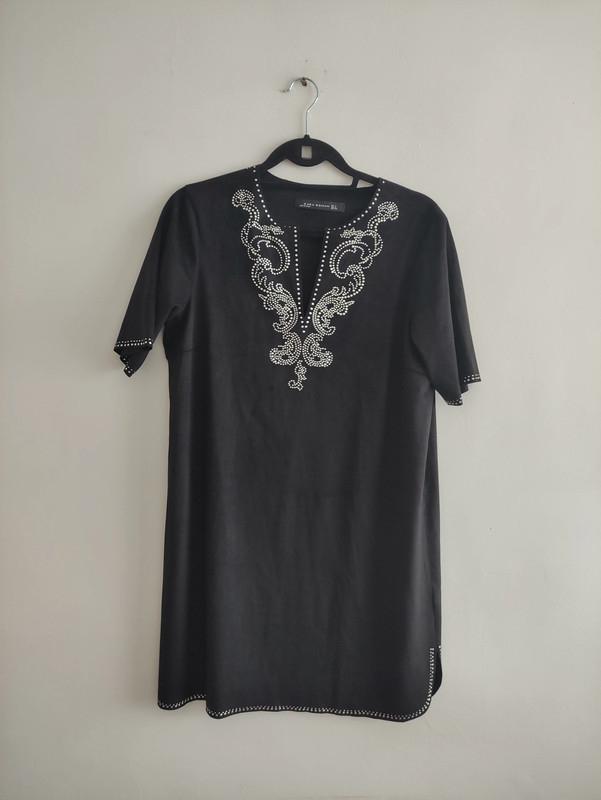 Front view of a black t-shirt with decorative embroidery on the neckline and short sleeves.