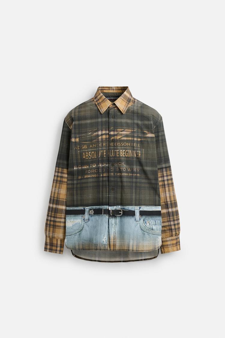 Front view of a checked shirt with 'ACSB ANDERSSON BELL' text print and belt over printed jeans.