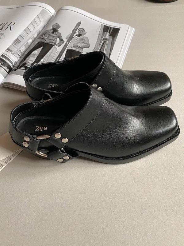 Black leather shoes with metal buckles on a table, next to an open black and white magazine with models.