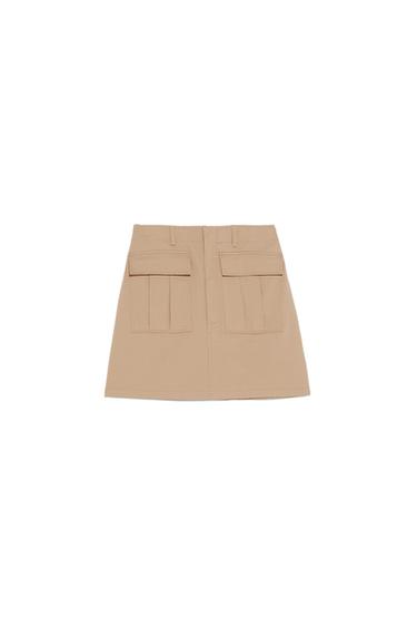 Beige cargo-style mini skirt with two large flap pockets on the front and belt loops, set against a white background.
