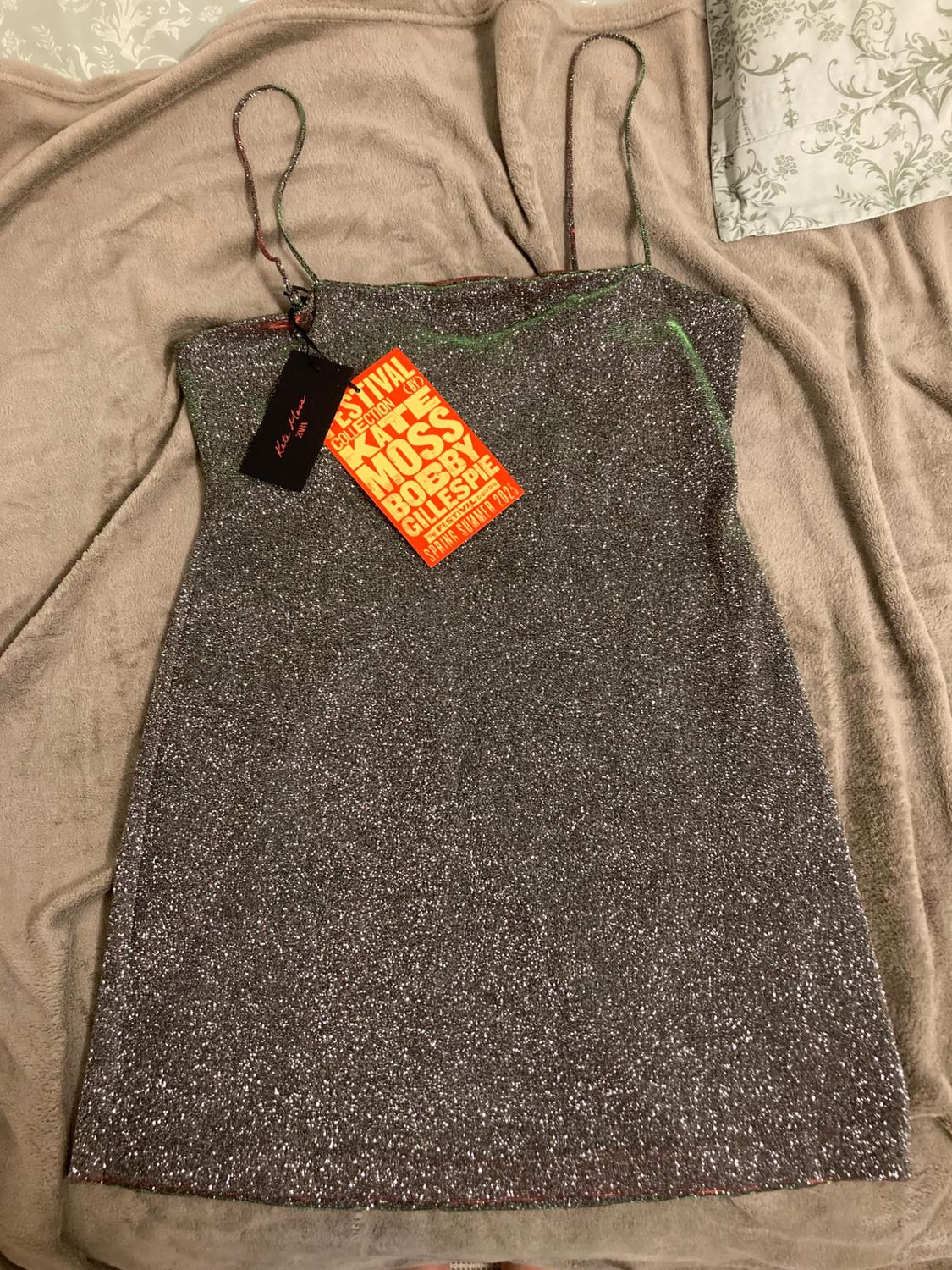 Sparkly dress with spaghetti straps over beige fabric. Red label with text: "Festival Collection 44 Moss Bobby Gillespie Spring Summer 2023".