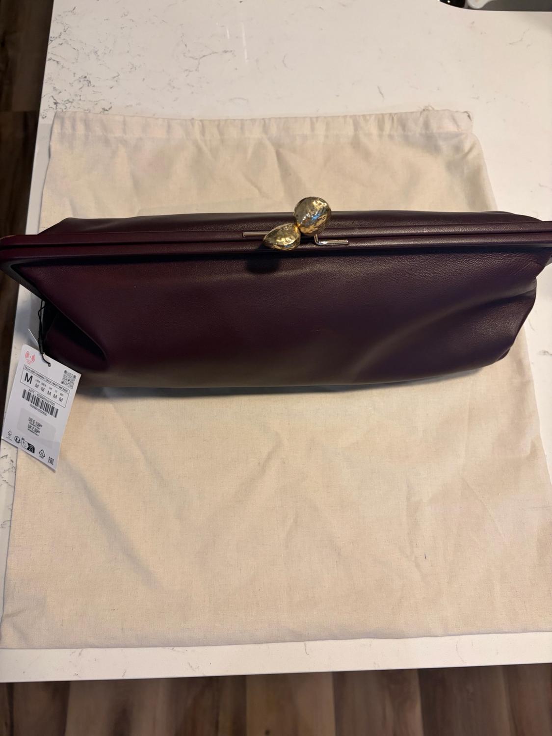 Burgundy handbag with gold fastening on a beige cover. Text: M M M M M ART: 6009/510/200 US $ 129 UK £ 89.