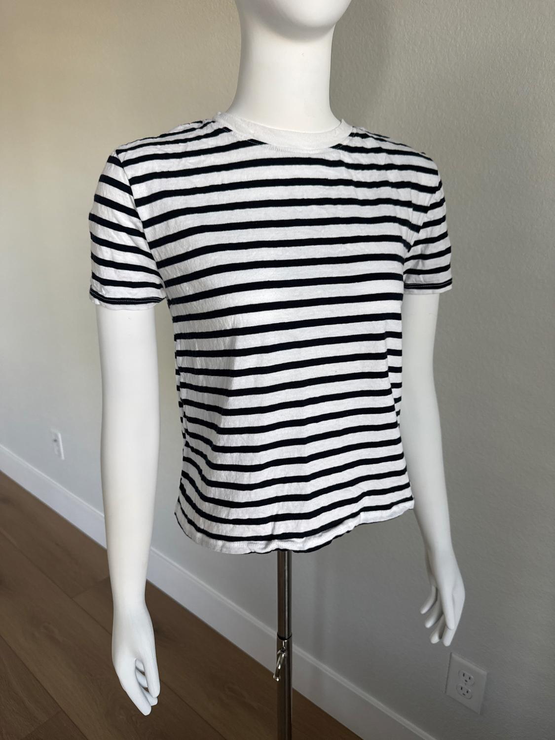 White mannequin wearing a short-sleeved t-shirt with black and white horizontal stripes. Light wall background and wooden floor.