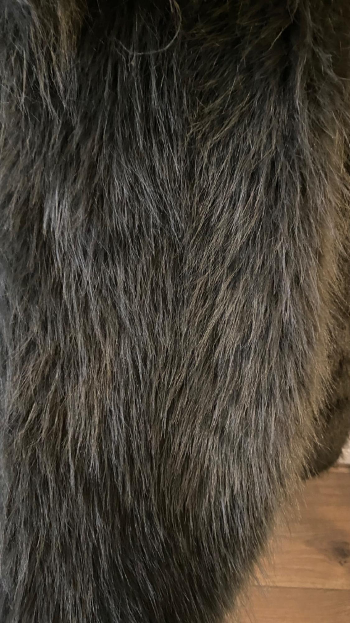Close-up of a dark, dense hair texture, with brown and grey tones, on a wooden background.